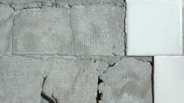 Old house interior ceramic tiles falling off from the wall in the bathroom tilt up