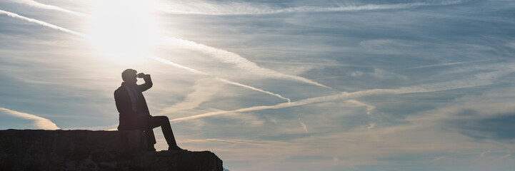 Wide panorama view of businessman in a suit sitting on a wall © Gajus