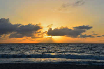 colorful sunset over the Atlantic Ocean, beach, coastline, waves. the light of the sun making its way through the clouds on the horizon, Punta Cana
