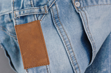 part of denim pants with back pockets and label, close-up