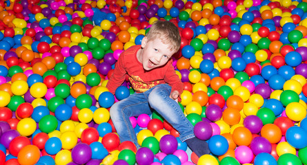 Fototapeta na wymiar little boy having fun in a pool of colorful balls in the entertainment center