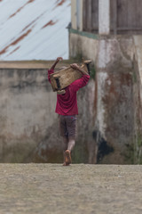 Sao Tome and Principe, a boy walking in a village with hand-made wooden skateboard
