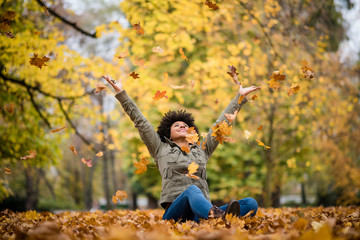 Girl playfully throwing up leaves over her head