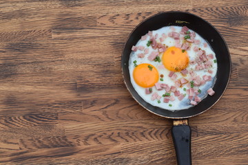 pan fried egg with ham and bread on wood background for breakfast, top view