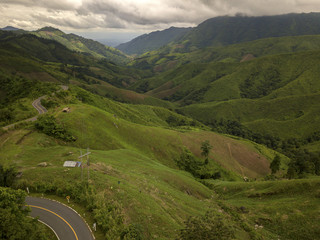 Aerial view of countryside road passing through the lush greenery and foliage tropical rain forest mountain landscape in the Northern Thailand