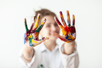 Happy woman showing hands painted in colorful paints