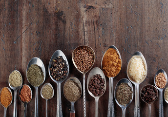 Different spices in  spoons on a wooden background.