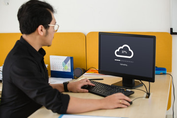 Businessman doing cloud uploading on computer at office - 219383224