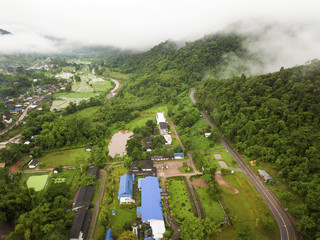 Aerial view of a village in the lush green rain cloud cover tropical rain forest mountain during the rainy season on the Doi Phuka Mountain reserved national park the northern Thailand
