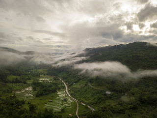 Aerial view of a village in the lush green rain cloud cover tropical rain forest mountain during...