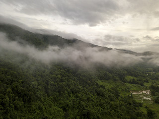 Aerial view of a village in the lush green rain cloud cover tropical rain forest mountain during the rainy season on the Doi Phuka Mountain reserved national park the northern Thailand