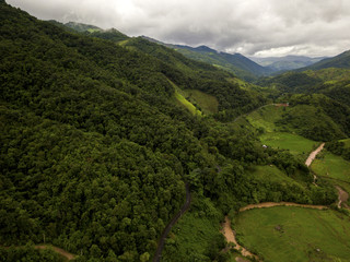 Aerial view of a village in the lush green rain cloud cover tropical rain forest mountain during...