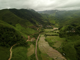 Aerial view of a village in the lush green rain cloud cover tropical rain forest mountain during...