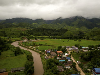 Fototapeta na wymiar Aerial view of a village in the lush green rain cloud cover tropical rain forest mountain during the rainy season on the Doi Phuka Mountain reserved national park the northern Thailand
