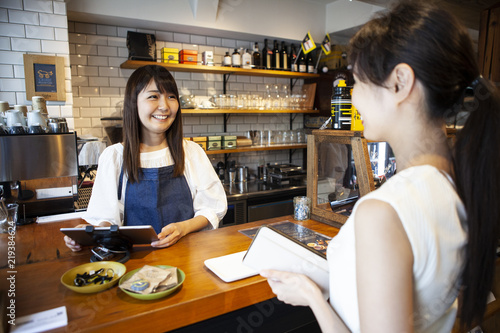 笑顔のカフェ店員とお会計をしようとする女性 Wall Mural Monet 笑顔のカフェ店員とお会計をしようとする女性 Wall Mural Monet