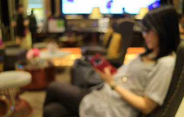 Out of focus shot of a young woman in the lobby looking at cell phone in her hand