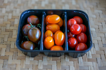 Tomato Varieties ,Type and color mixed together in black plastic basket on wooden floor