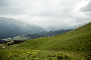 green slope of a high mountain during a thunderstorm with clouds in the sky