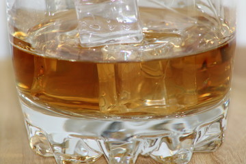 Cognac into glass cup with ice cubes