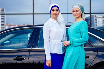 two beautiful perfect girl makeup in muslim dress and turban on head standing in front of the car