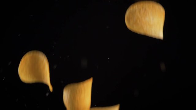 potato chips in free fall on a black background. Slow motion. The view from the side. Pringles