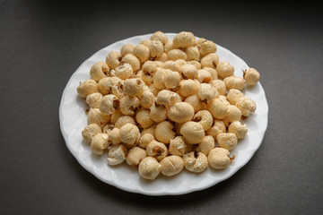 White dish with popcorn on a dark background.
