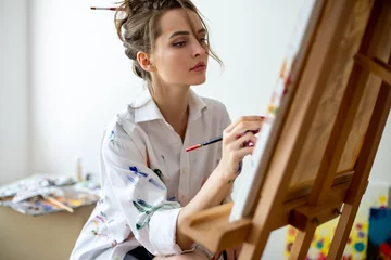 Fotobehang Schilderij Closeup of beautiful woman painting on canvas in studio  © GVS