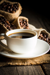 Coffee cup and beans on a rustic background. Coffee Espresso and a piece of cake with a curl. Cup of Coffee and coffee beans on table.