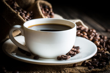 Coffee cup and beans on a rustic background. Coffee Espresso and a piece of cake with a curl. Cup of Coffee and coffee beans on table.