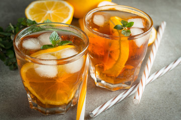 Glasses of cold ice tea with lemon, ice, mint on background. Homemade lemonade. Spring and summer drinks and beverages concept. 