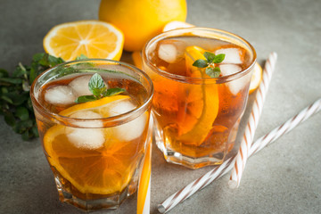 Glasses of cold ice tea with lemon, ice, mint on background. Homemade lemonade. Spring and summer drinks and beverages concept. 