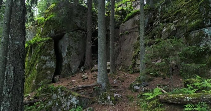 Rocky cliffs with moss and cave in the dark and green forest during summer day. Nuuksio. Espoo. Finland. Scandinavia