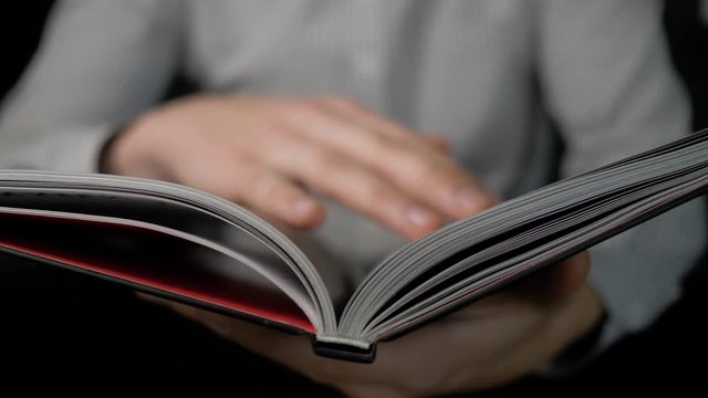 man's hands flipping through the book, lying on his knees. 4K