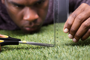 Man Cutting The Measured Grass With Scissor