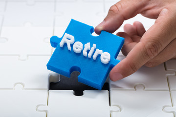 Person placing last retire piece into jigsaw puzzle
