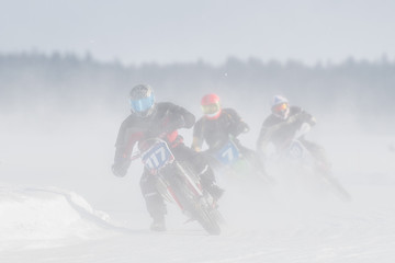 Fototapeta na wymiar Motorcyclist racing on ice track in the middle of dusting snow
