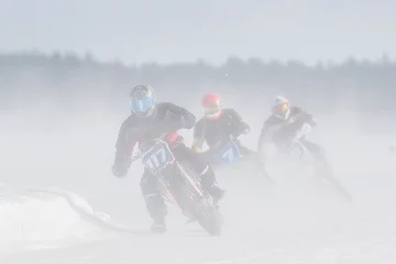 Fotobehang Motorcyclist racing on ice track in the middle of dusting snow © Juha Saastamoinen