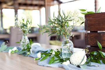 Wedding. Banquet. Table for guests, covered with a tablecloth, decorated with candles, transparent glass vases, fresh flowers