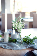 Wedding. Banquet. Table for guests, covered with a tablecloth, decorated with candles, transparent glass vases, fresh flowers