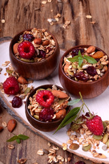 Granola decorated with raspberries in wooden bowls on the table