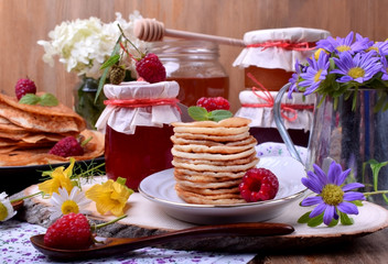 Stack of pancakes decorated with raspberry and mint on a white plate. Village style