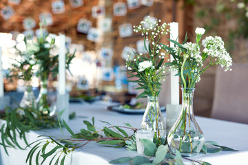 Wedding. Banquet. Table for guests, covered with a tablecloth, decorated with candles, transparent glass vases, fresh flowers and served with cutlery and crockery with rope decorations on background