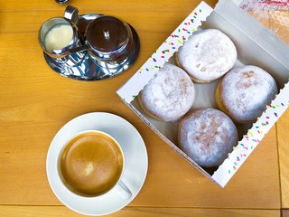Delicious freshly baked doughnuts with powdered sugar and cup of coffee on rustic wooden...