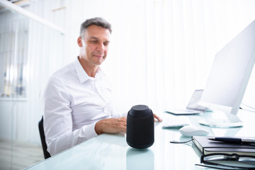 Man Listening To Wireless Speaker In Office