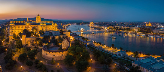 Fototapeta premium Budapest Hungary - Aerial panoramic skyline view of Budapest at blue hour with Buda Castle Royal Palace, Szechenyi Chain Bridge, Parliament, St.Stephen's Basilica and sightseeing boats on River Danube