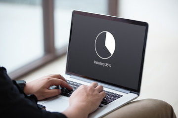 Man Installing update with circle load percentage waiting indicator concept on the laptop / computer screen at office - 219398228