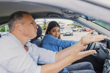 Driving school or test. Beautiful young woman learning how to drive car together with her instructor.