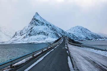Winter road over the sea with snowy peak on Lofoten Islands, Norway. Travel background