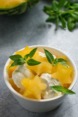 Stars of a ripe watermelon and ice cream in a white cup for dessert, mint and a cut watermelon in the background