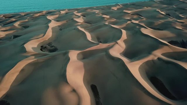 Desert landscape, wonderful sand dunes in sunset light. Aerial: horizon with an oringe desert and blue ocean. Gran Canaria